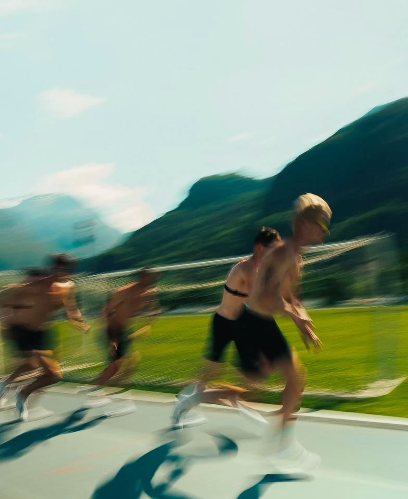 A long exposure of runners pushing off down a track, hills behind them.